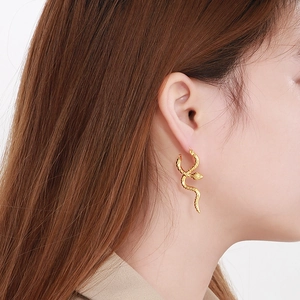 Detail of creative gold snake earrings showing textured scales and curved serpent design