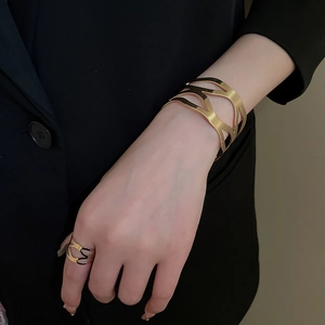 Close-up of a gold hollow geometric bracelet and matching ring set worn on a hand