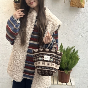 Detail of plush brown jacquard tote bag with fuzzy white vest in a lifestyle setting