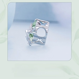 Macro shot of silver butterfly charm with green gemstone and S925 engraving detail