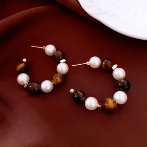 Vintage 16K gold plated tiger eye and pearl hoop earrings on luxury velvet background