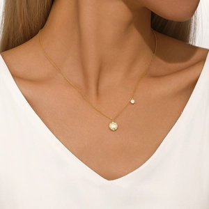 Detail of gold double-pendant necklace with white shell flower and sparkling zircon