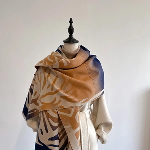 Detail of gradient cashmere-like scarf with large abstract leaf patterns in brown and blue