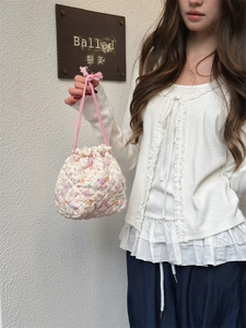 Detail of a quilted floral drawstring pouch held by a model for travel storage