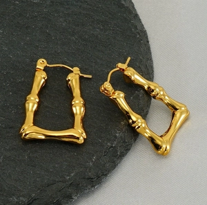 Détail macro montrant la texture bambou dorée et le fermoir sécurisé des boucles d'oreilles