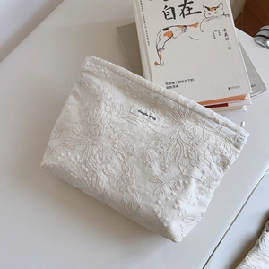 Close-up of floral embroidery on a cream cotton clutch bag with a simple wish label