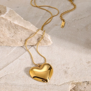 Elegant gold heart pendant necklace in stainless steel on a textured stone surface