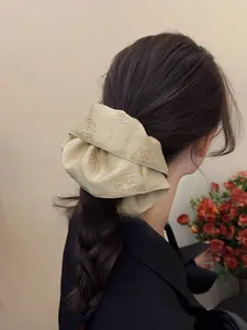 Detail of champagne gold jacquard satin scrunchie styled on a classic ponytail