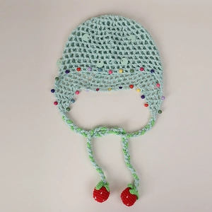 Close-up of light green knit beanie featuring colorful beads and 3D strawberry pendants