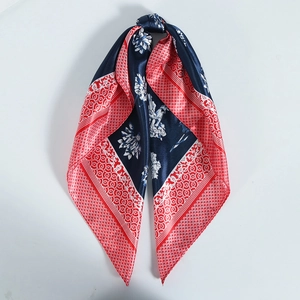 Close-up of knotted satin square scarf featuring blue and red floral geometric patterns