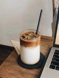 Close-up of ribbed heat-resistant glass cup with iced latte in home office setting