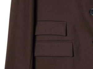 Detail view of the brown blazer showing fabric texture and pocket with black button