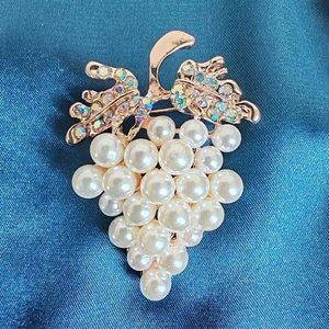 Baroque grape brooch with white pearls and iridescent rhinestones on blue silk fabric