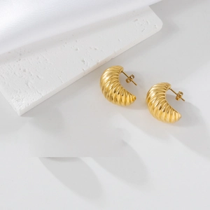 Macro shot of 18K gold plated spiral crescent earrings on white satin fabric