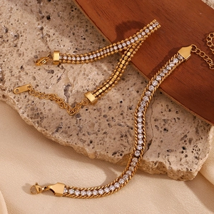 Detailed view of layered 18K gold plated bracelets with zircons on natural stone