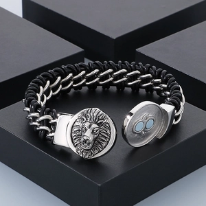 Detail of silver lion head emblem on black braided leather bracelet with magnetic clasp