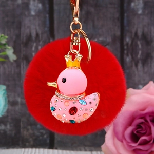 Cute pink metal duck keychain with red pompom and sparkling crystals on golden ring