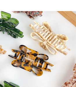 Detail view of retro acetate bow hair claws in marble and tortoiseshell patterns