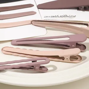 Detailed view of matte dusty pink and purple duckbill hair clips on a ceramic plate
