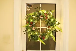 Close-up of artificial Christmas wreath with pine needles, berries and warm LED lights