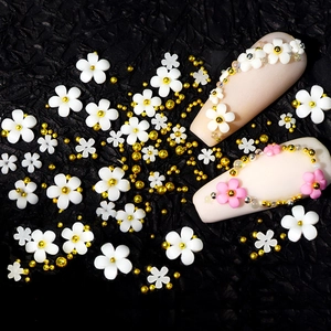 Macro shot of white and pink resin five-petal flowers with gold beads for nail art DIY