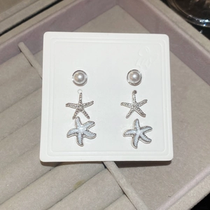 Macro view of starfish stud earrings with pearls on display card in velvet box