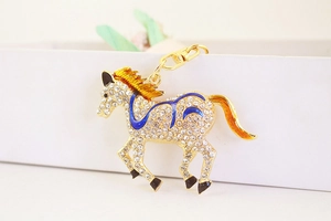 Detailed macro view of golden running horse keychain with sparkling crystals and blue enamel