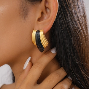 Close-up of vintage golden ribbed earrings with black enamel inlay on a model