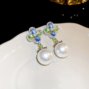 Detailed shot of baroque freshwater pearl drop earrings with clover gemstone studs