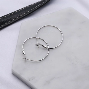 Detail of silver large hoop earrings on marble display with needle clasp structure