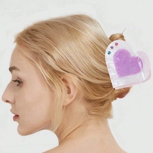 Detail of purple marble acrylic heart hair claw clip with rhinestones on a blonde model