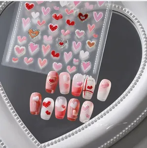 Macro shot of 3D heart nail art stickers in red and pink designs on a mirror tray