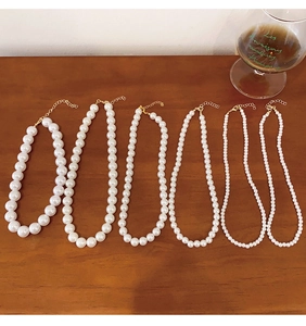 Detail view of six pearl necklaces with varying bead sizes and gold clasps