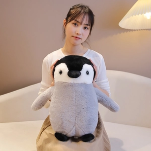 Adorable penguin plush toy held by a model showing its soft fluffy texture and size.