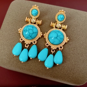 Detail of vintage bohemian drop earrings with turquoise stones on a gold textured base
