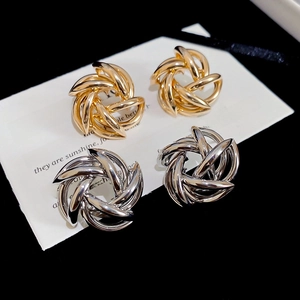 Detailed close-up of polished gold and silver twisted knot stud earrings on white card