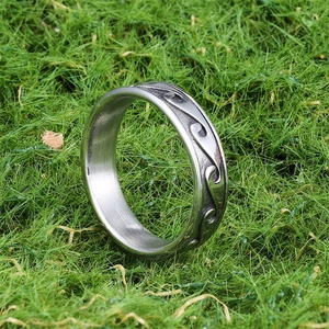 Minimalist silver wave pattern stainless steel ring standing on green grass