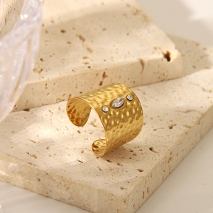 Macro shot of hammer-textured gold ring with marquise crystal on beige stone base