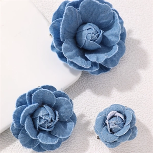 Three sizes of denim camellia flower brooches in blue fabric on a white background