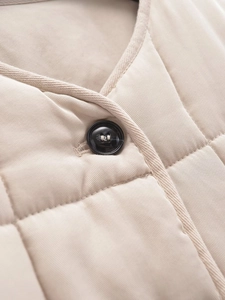 Detailed close-up of a quilted cotton jacket featuring a black button and diamond stitching