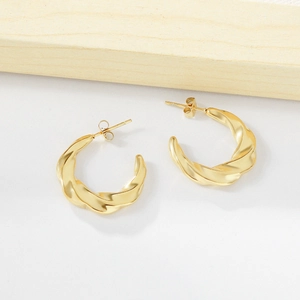 Macro shot of 18K gold plated stainless steel C-shape twisted earrings with metal texture