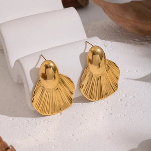 Macro detail of gold-toned shell-shaped leaf earrings with radiating stripe textures
