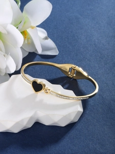 Detailed macro view of a gold heart bracelet with black inlay and sparkling zircon stones