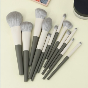 13-piece portable travel makeup brush set with soft dual-tone handles on a warm background