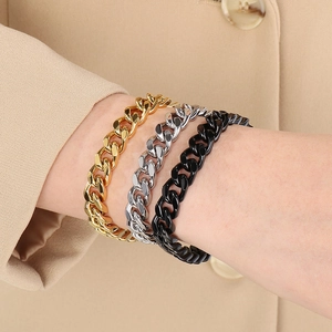 Close-up of Cuban link bracelets in gold, silver, and black finish on a model wrist