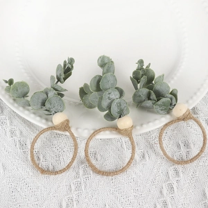 Set of 3 eucalyptus leaf napkin rings with wooden beads and rustic twine on white plate