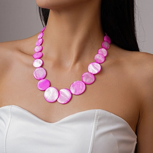Detail of fuchsia shell bead necklace showing natural iridescent texture on model