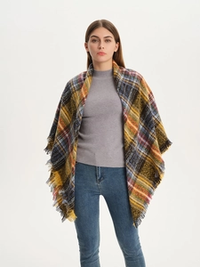 Front view of model wearing a thick yellow and blue plaid scarf with fringe details