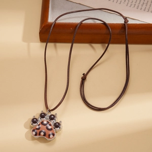 Detail of leopard print paw pendant with black pads and a brown braided cord necklace