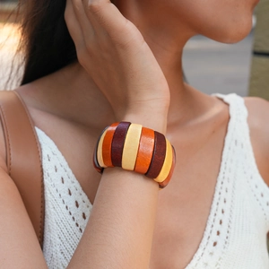 Close-up of bohemian wooden beaded bracelet featuring geometric brown and orange charms